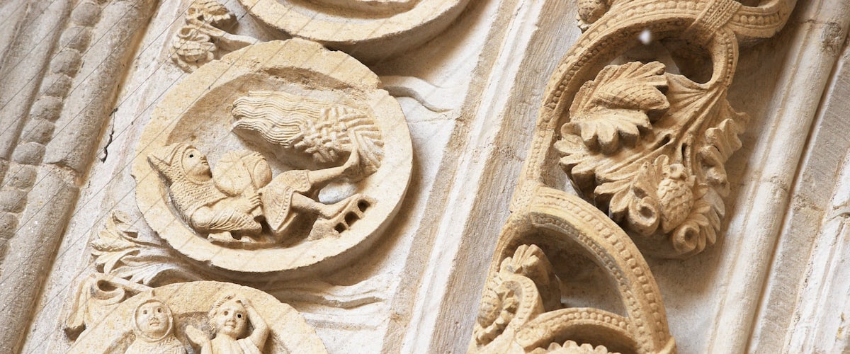 Sculptures détaillées dans la pierre, représentant des anges et des motifs floraux, ornant une colonne.