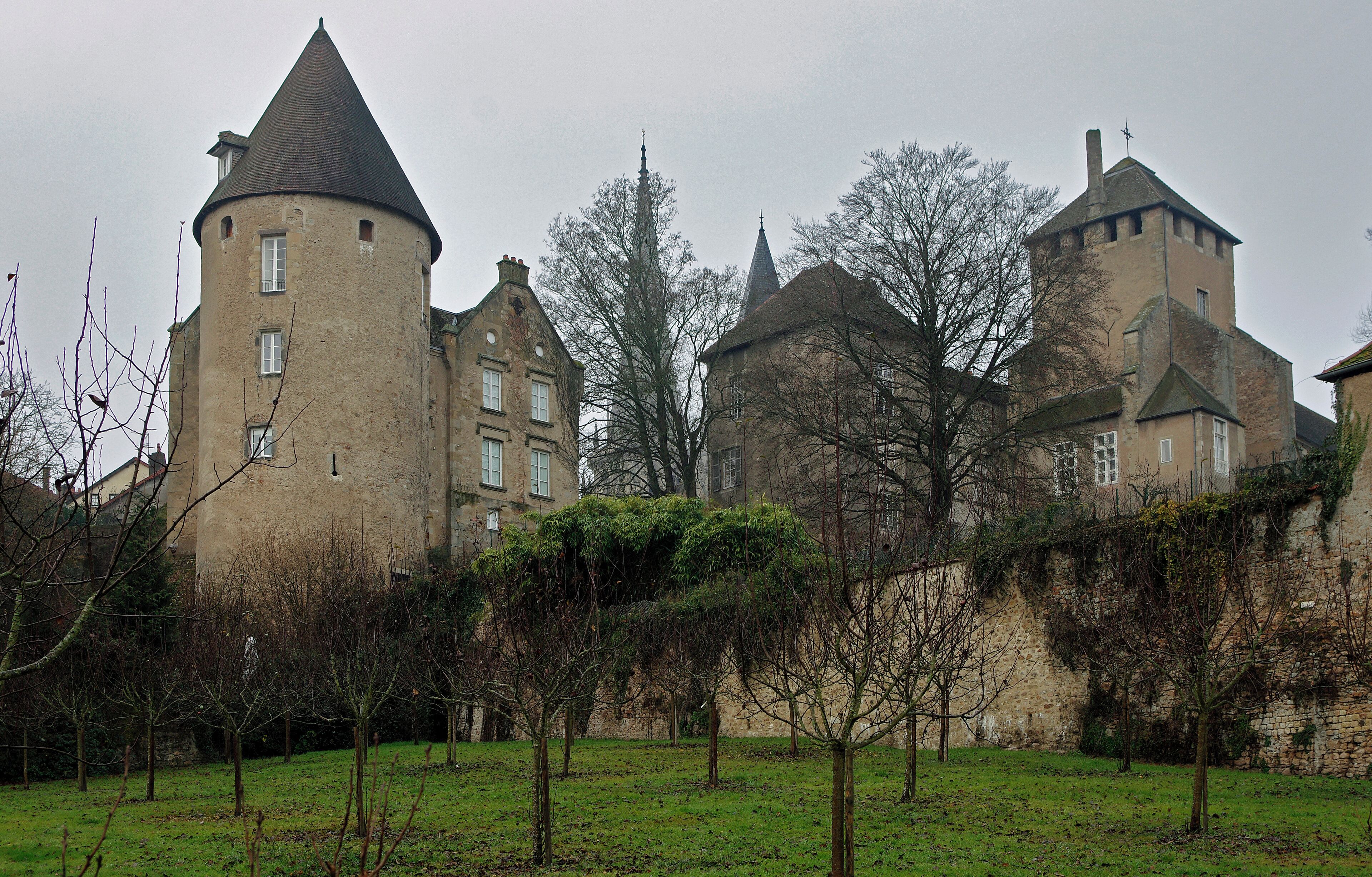 A historic castle with multiple towers and a surrounding grassy area with trees.