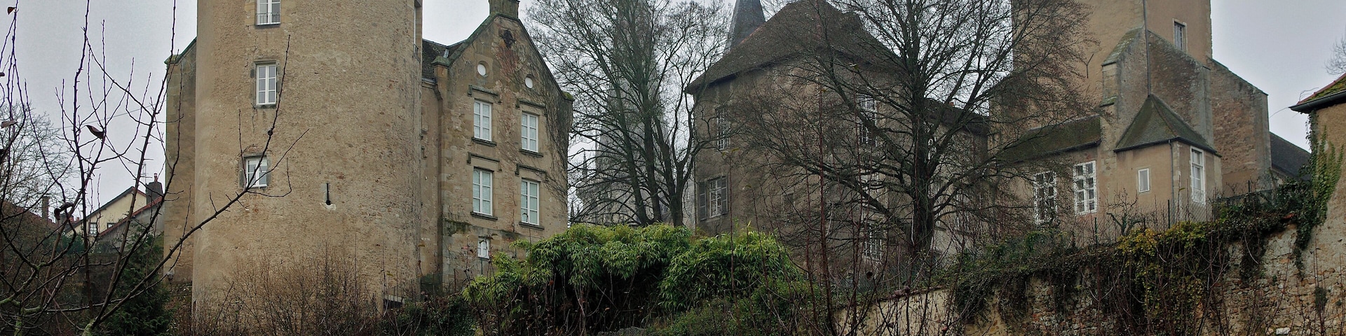 A historic castle with multiple towers and a surrounding grassy area with trees.