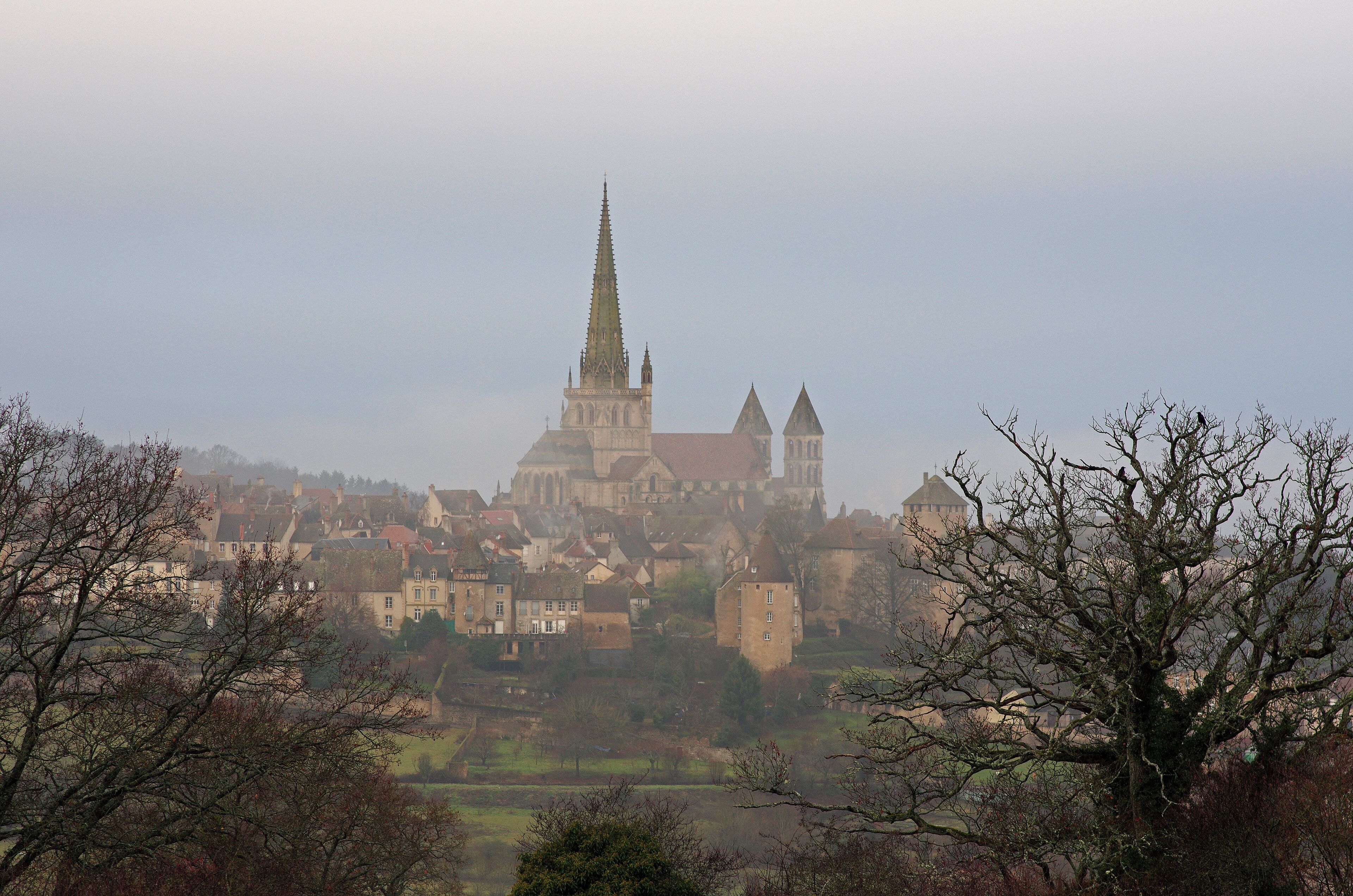 A historic town with a prominent church featuring a tall spire, surrounded by residential buildings and trees.