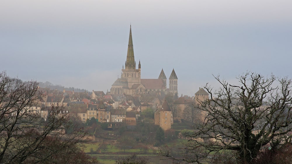 A historic town with a prominent church featuring a tall spire, surrounded by residential buildings and trees.
