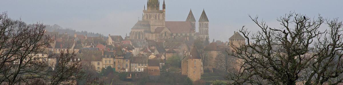 A historic town with a prominent church featuring a tall spire, surrounded by residential buildings and trees.