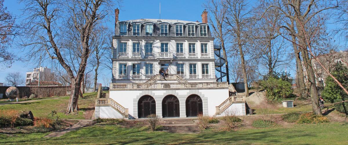 A large, multi-story building with a symmetrical facade, arched windows, and a central staircase leading to a balcony.