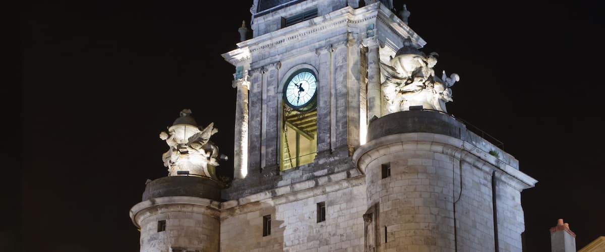 A historic tower with a clock, illuminated at night.