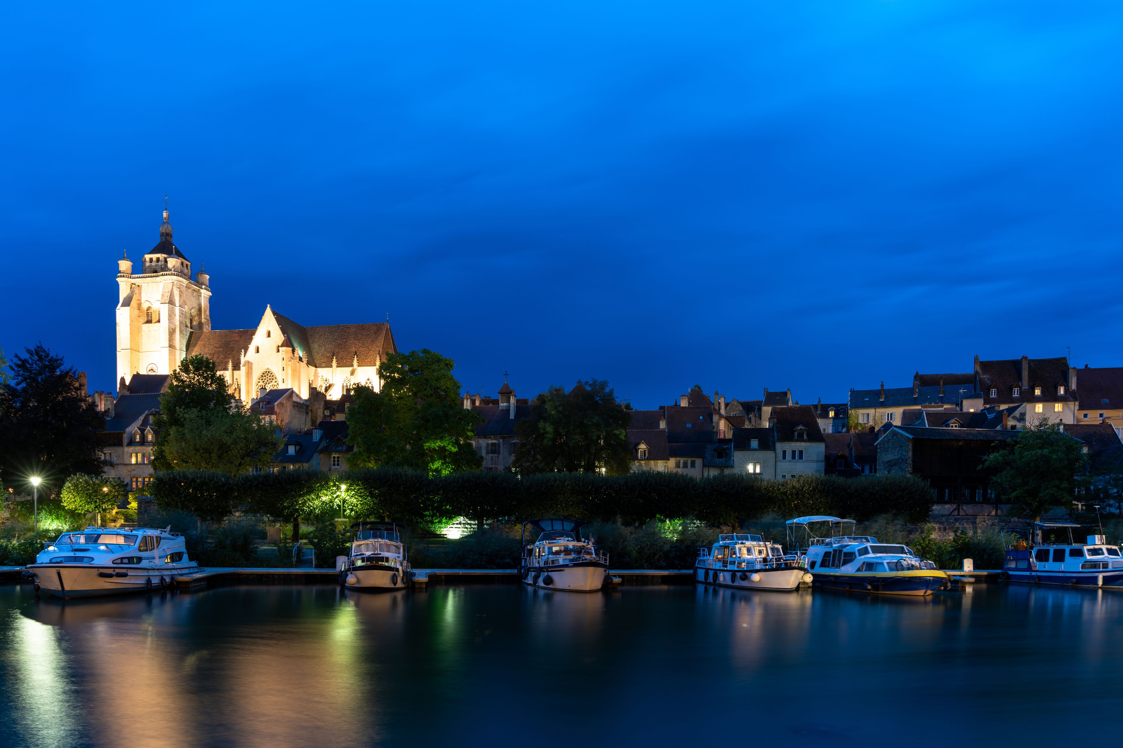 A historic church with a prominent tower, surrounded by residential buildings and a calm water body with boats.