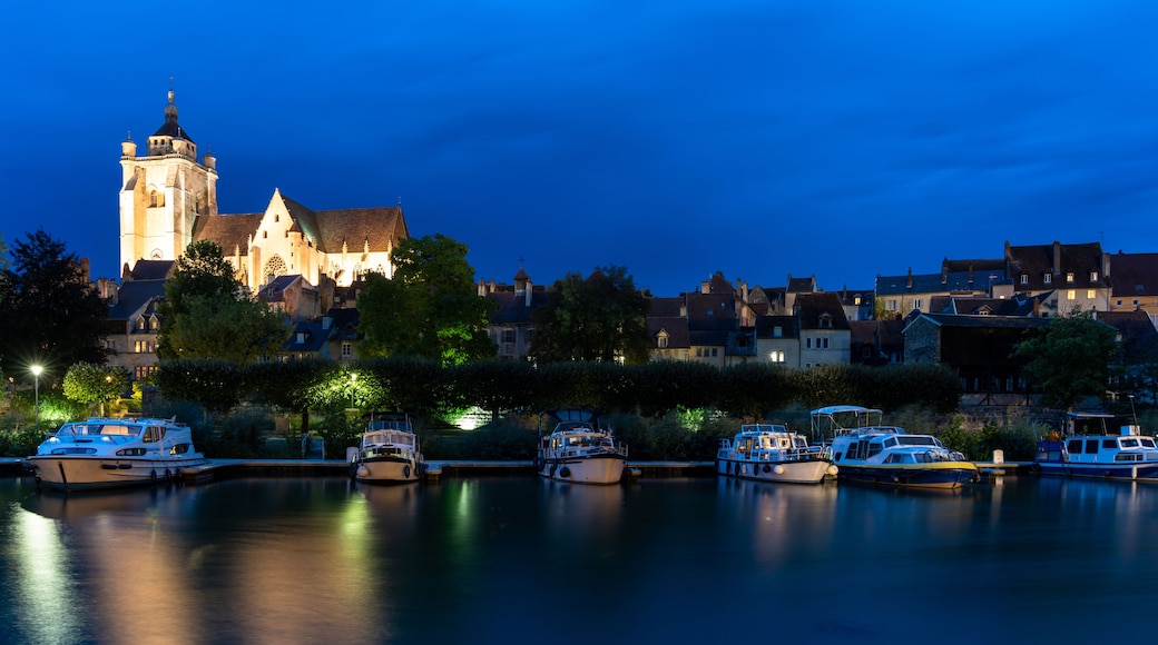 A historic church with a prominent tower, surrounded by residential buildings and a calm water body with boats.