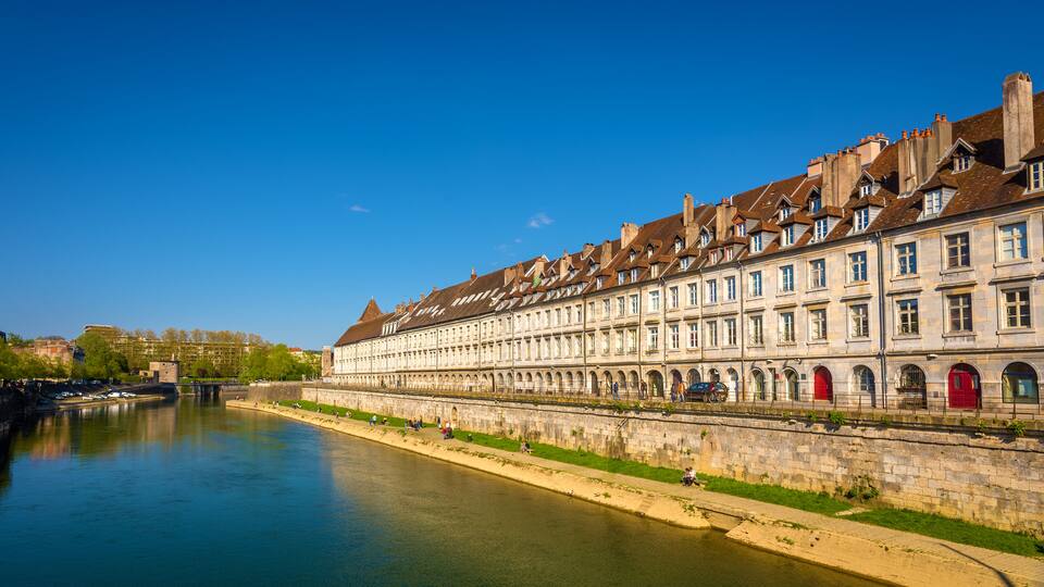 A river with a row of historic buildings along its banks.