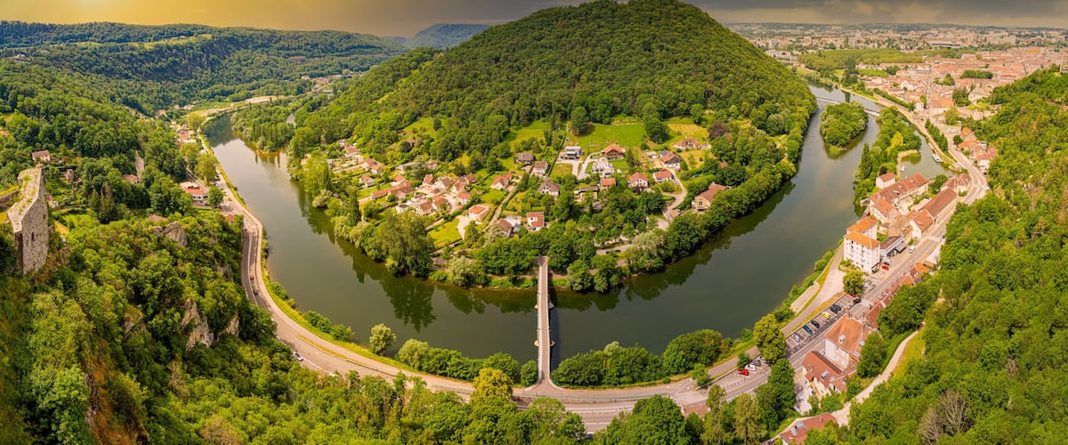 A river winding through a town surrounded by hills, with a prominent hill in the center.