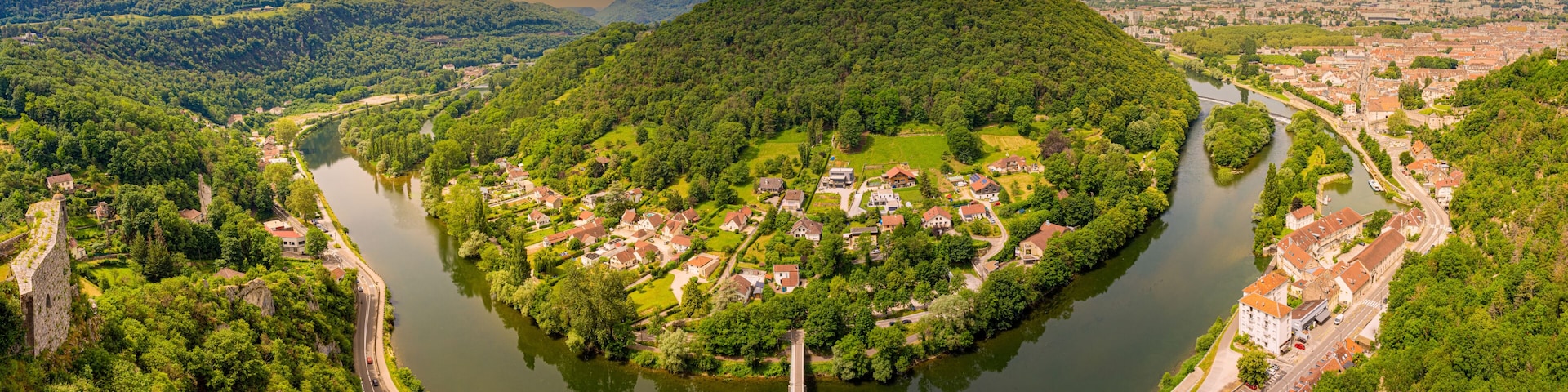 A river winding through a town surrounded by hills, with a prominent hill in the center.