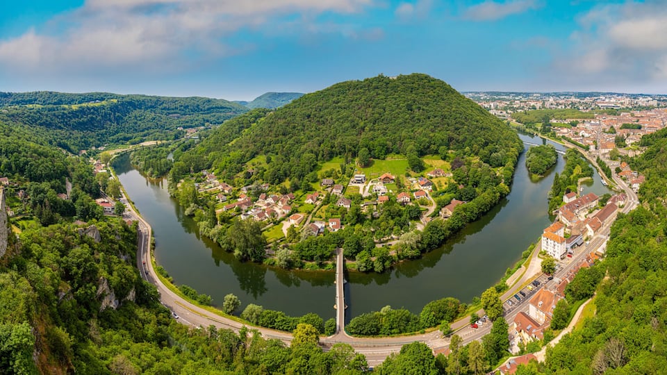 A river winding through a town surrounded by hills.