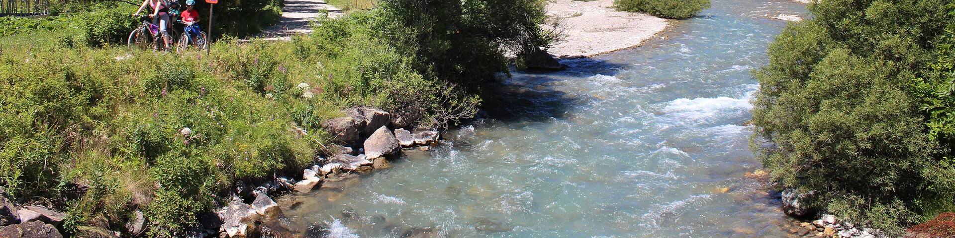 A river flowing through a mountainous landscape with lush greenery and rocky terrain.