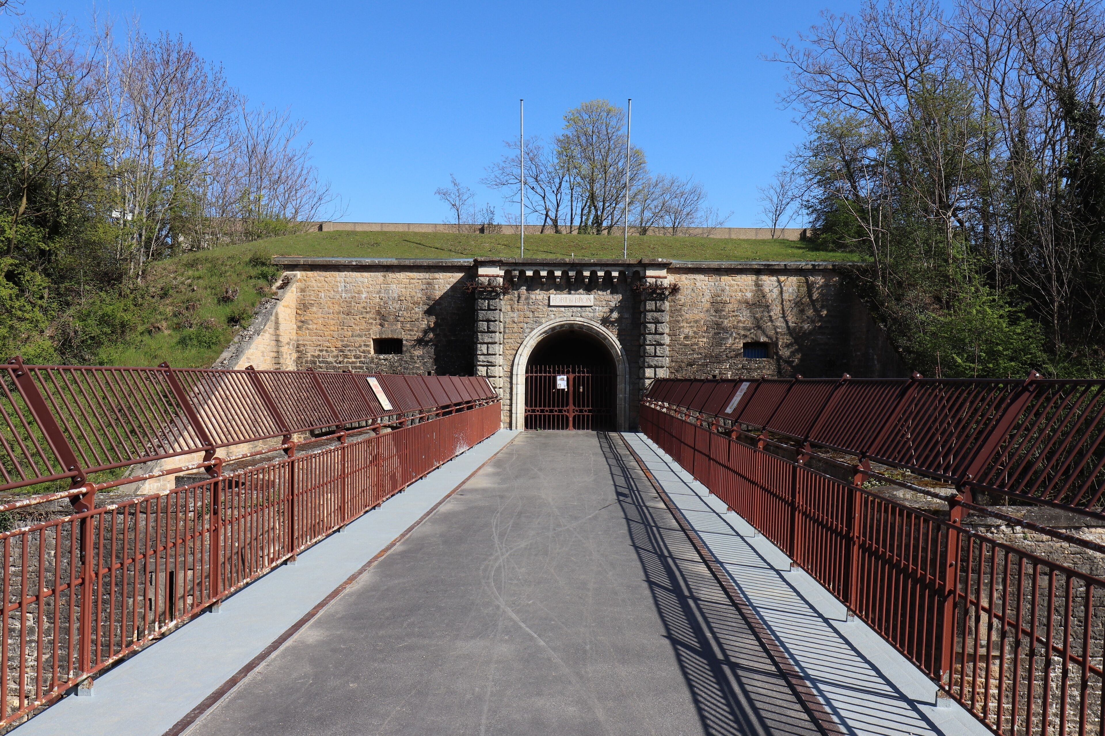 A stone bridge with metal railings leading to a tunnel entrance.
