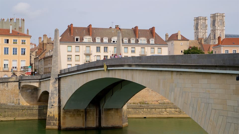 A stone bridge over a river with buildings in the background.