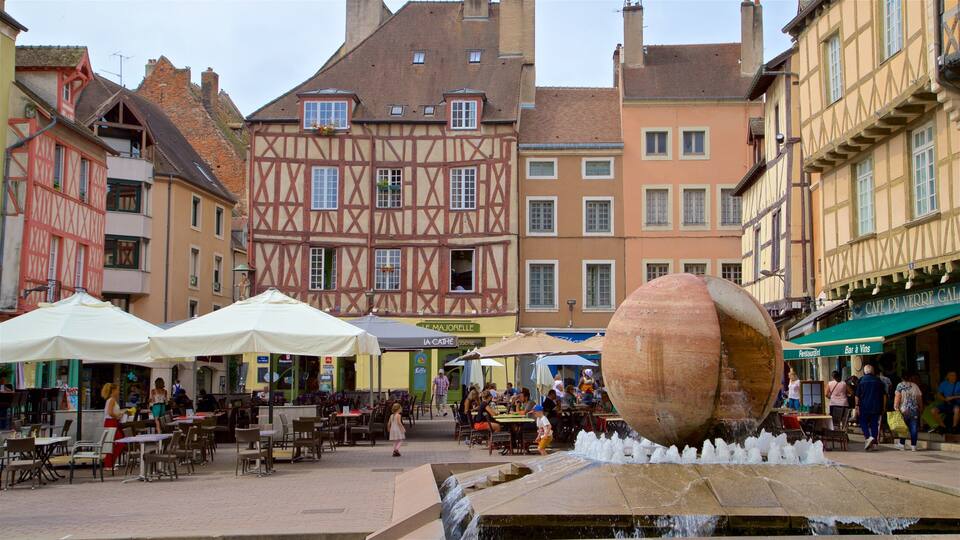 A bustling outdoor café with tables and umbrellas, surrounded by historic half-timbered buildings.