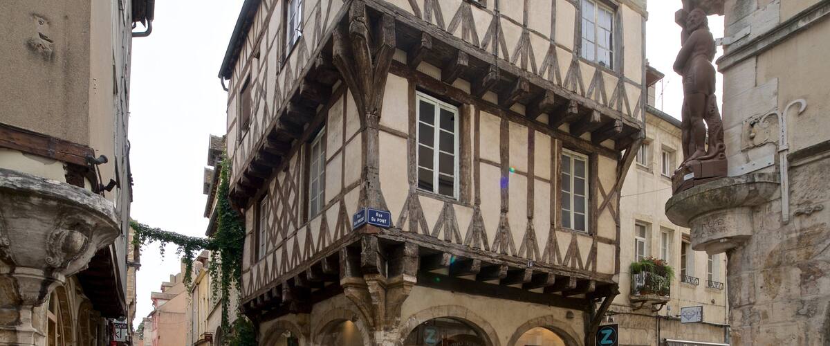 A narrow medieval street with half-timbered buildings, a café, and a bar.