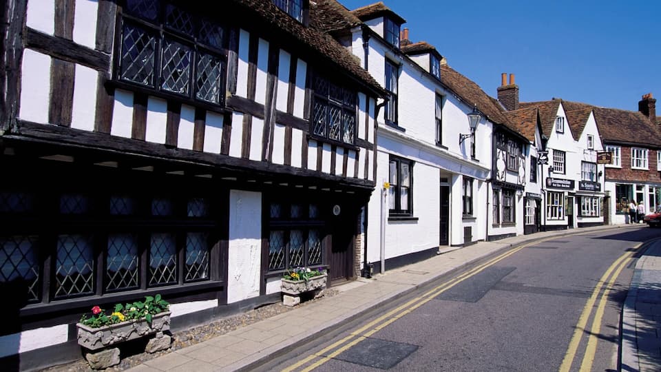 A street with traditional half-timbered buildings, a clear blue sky, and a double yellow line on the road.