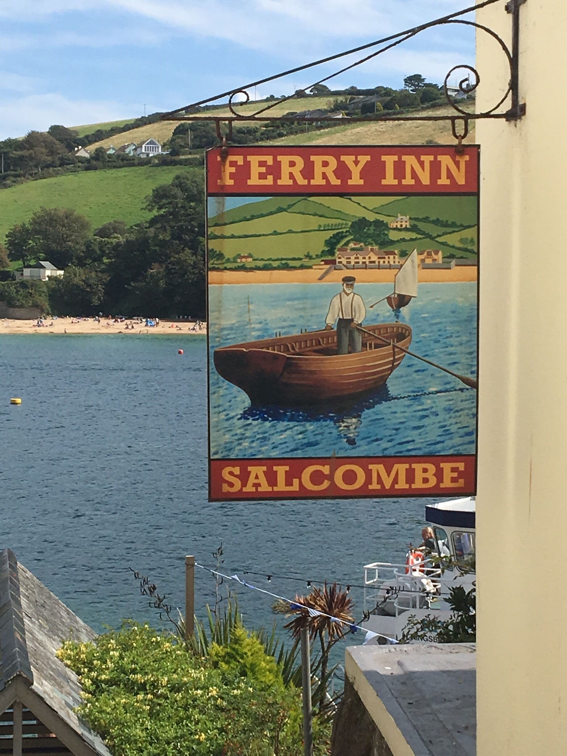 Placa do Ferry Inn em Salcombe com a ilustração de um homem em um barco na água.