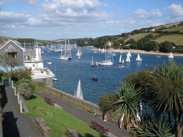 A harbor with sailboats, a grassy path, and a stone building.