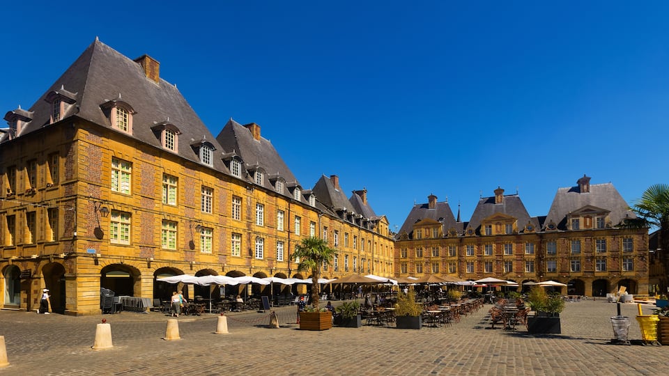 A historic European square with cobblestone pavement, traditional buildings, and outdoor seating areas.