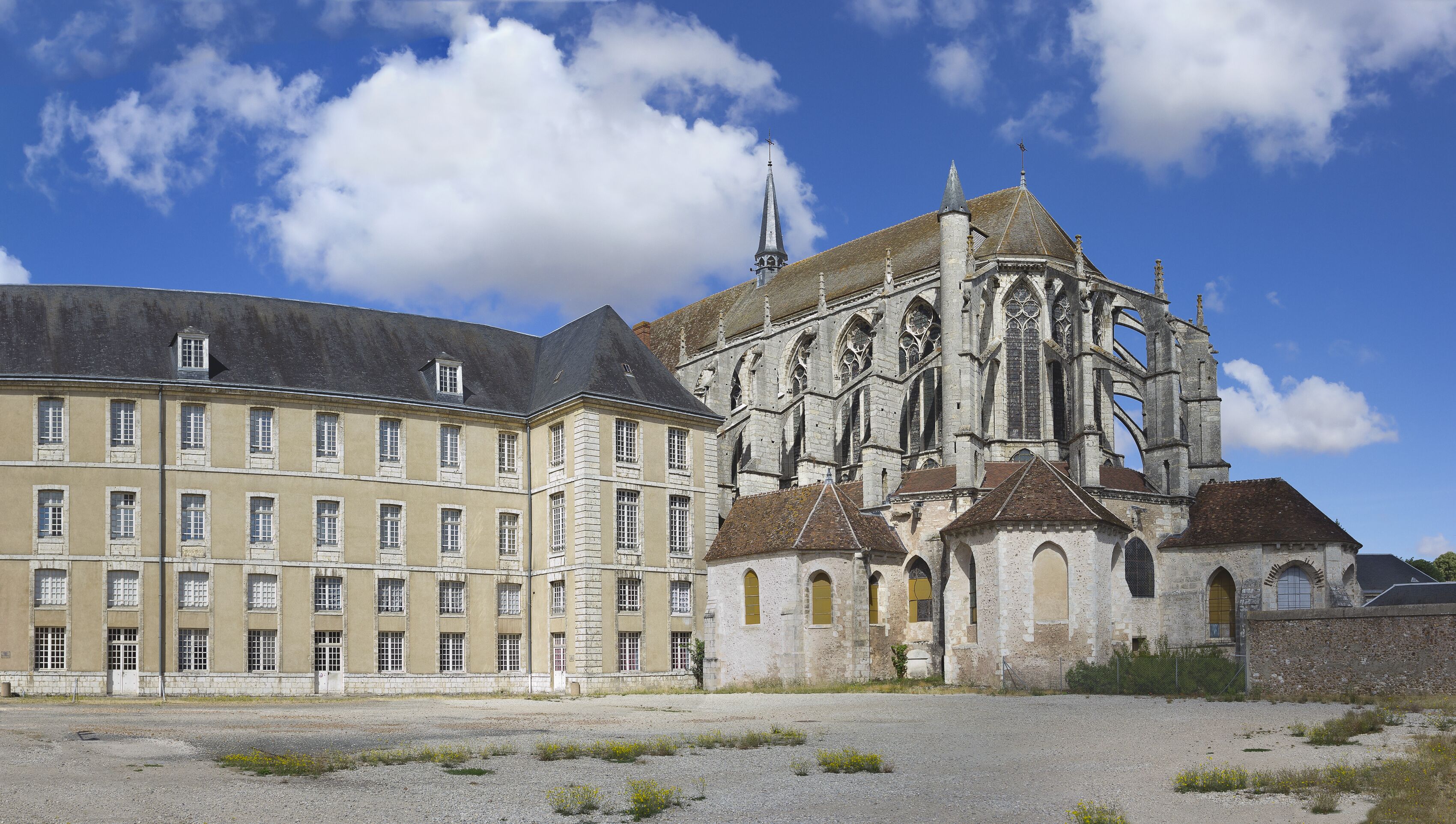 A historic building with a large tower and a smaller adjacent building with multiple windows.