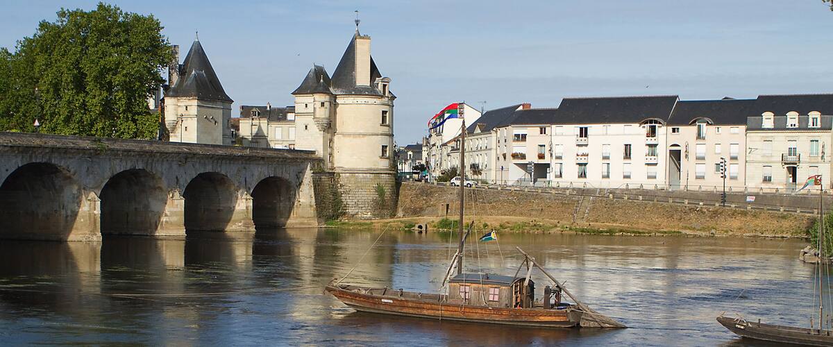 A river with a bridge, a castle, and a boat.