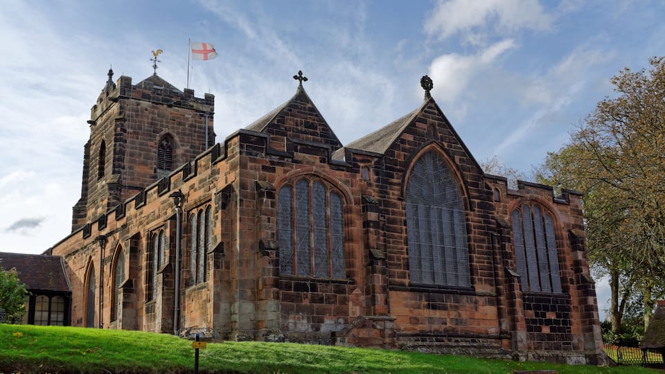 A historic church with large arched windows and a flag on top.