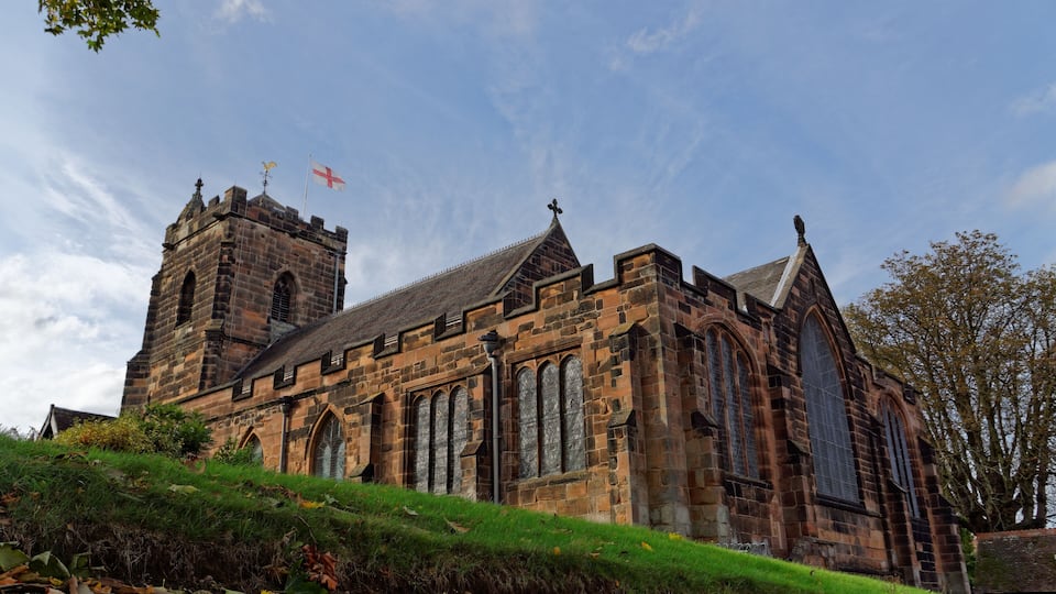 A historic stone church with a prominent tower and large arched windows.