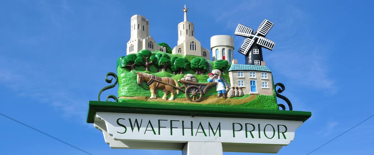 A sign with a windmill, a church, and a horse-drawn cart.