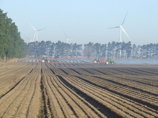 Two types of farming Parked up tractors with the wind farm of North Pickenham in the distance.