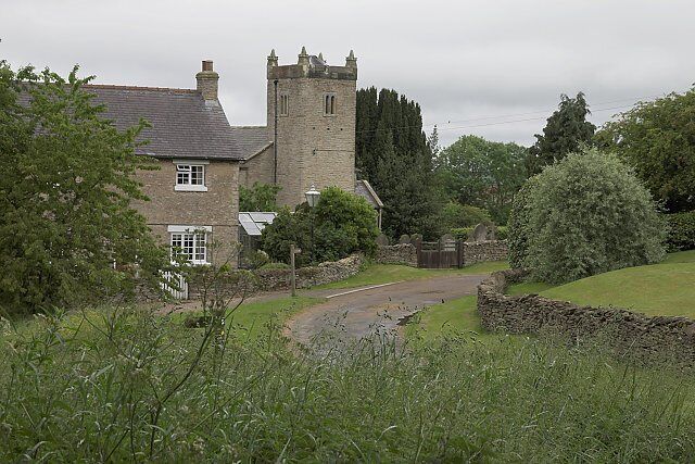 View along Low Field Lane, Cold Kirby, North Yorkshire, looking southeast to the Old School House (left) and the west tower of St Michael's parish church