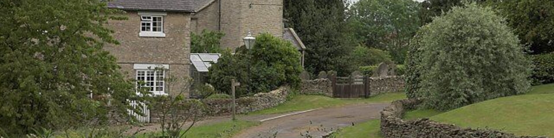 View along Low Field Lane, Cold Kirby, North Yorkshire, looking southeast to the Old School House (left) and the west tower of St Michael's parish church