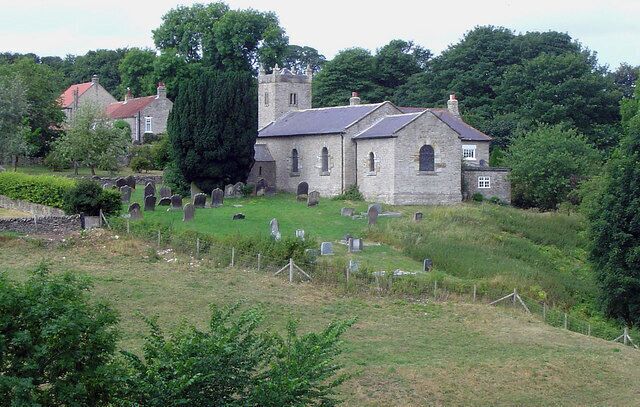 A church surrounded by a cemetery with gravestones and a tall tree.