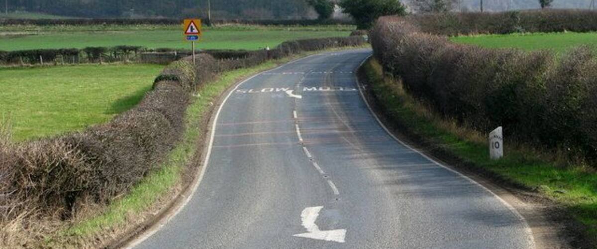 A rural road curving to the right with a warning sign for a junction ahead.