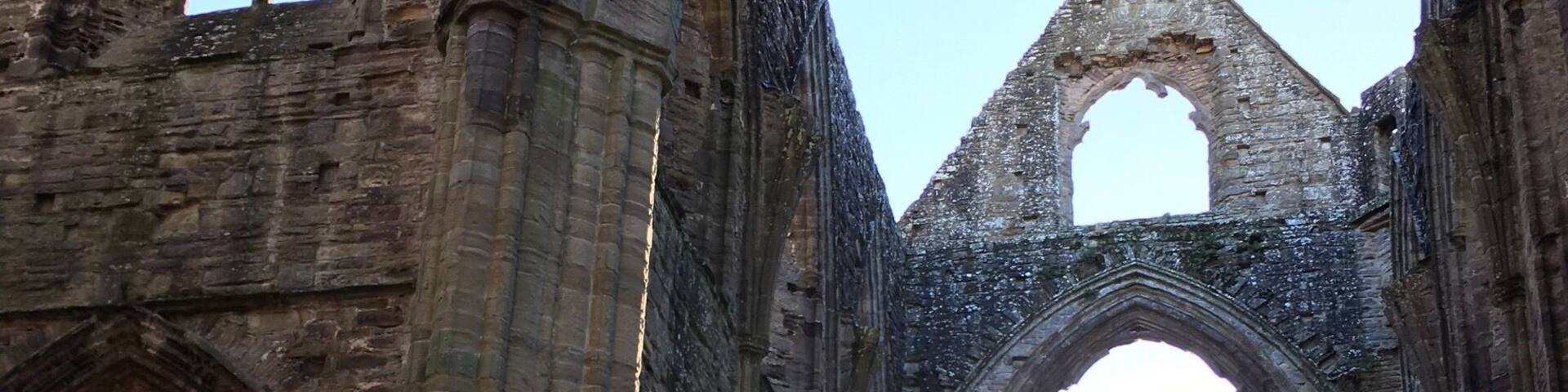 An ancient stone structure with large arches and columns, likely a historical building or cathedral.