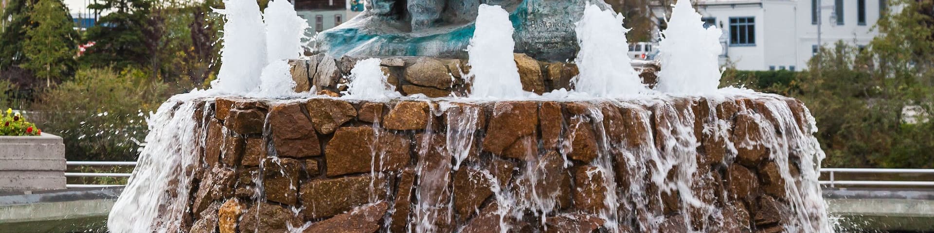 A statue with a child, a church with a blue roof, and a stone fountain.