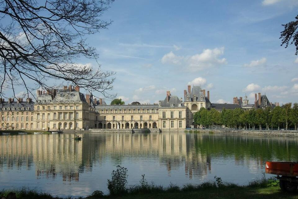 A historic building with a large courtyard and a lake.