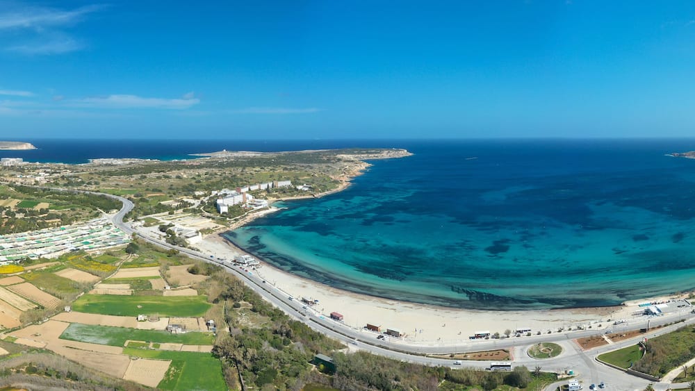 A coastal town with a large bay, a beach, and surrounding fields.