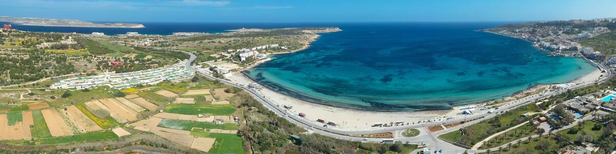 A coastal town with a large bay, a beach, and surrounding fields.