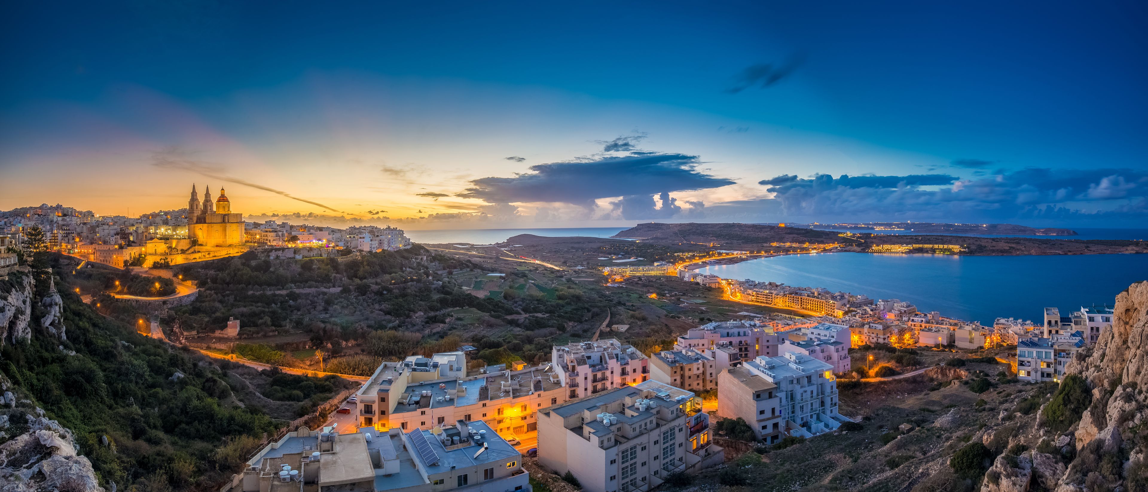 A coastal cityscape with a prominent church, residential buildings, and a large body of water.