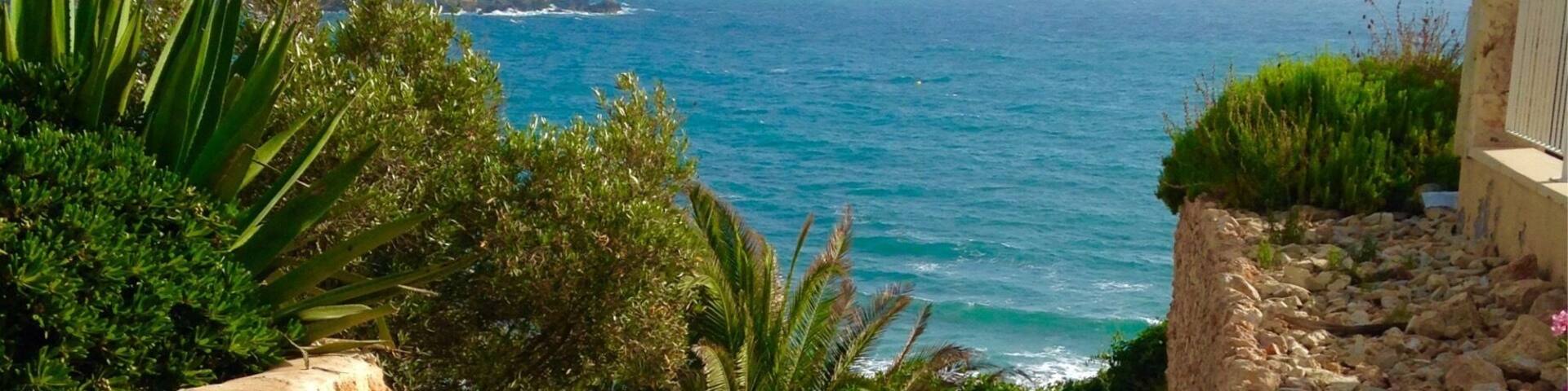 A stone staircase leading to a coastal area with a view of the sea and a bird flying overhead.