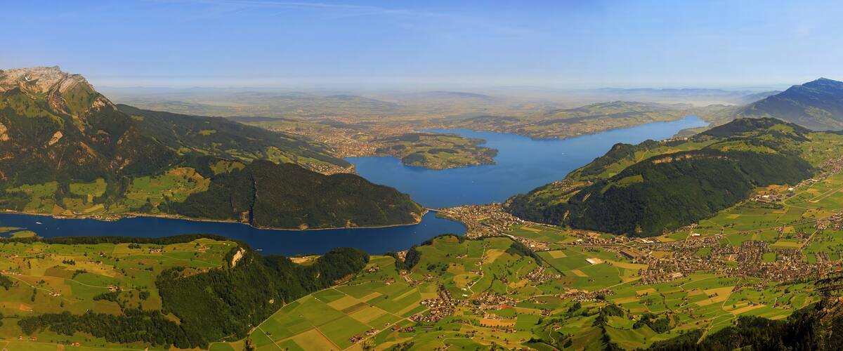 A mountainous landscape with a lake surrounded by green fields and a small town.