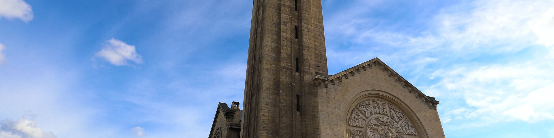 A tall church with detailed sculptures and a spire.