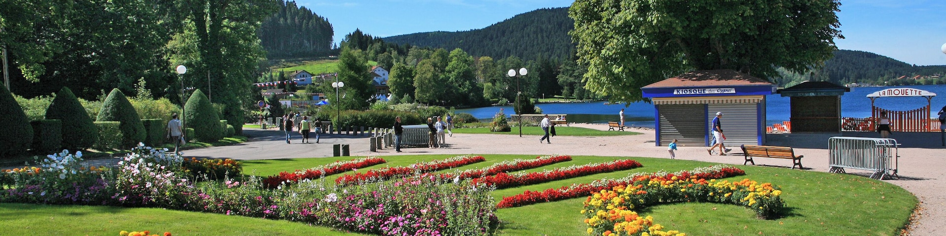 Un parque con parterres, bancos y un lago.