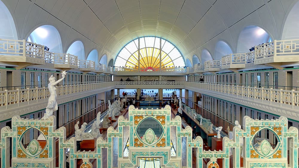 A grand interior with a large arched ceiling, ornate railings, and multiple levels.