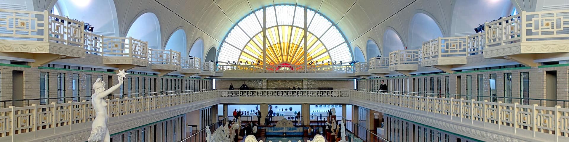A grand interior with a large arched ceiling, ornate railings, and multiple levels.
