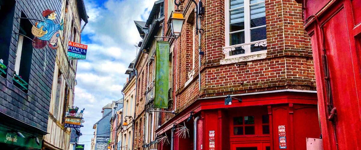 A cobblestone street lined with colorful buildings, including a red building with a sign that reads "HOTEL".