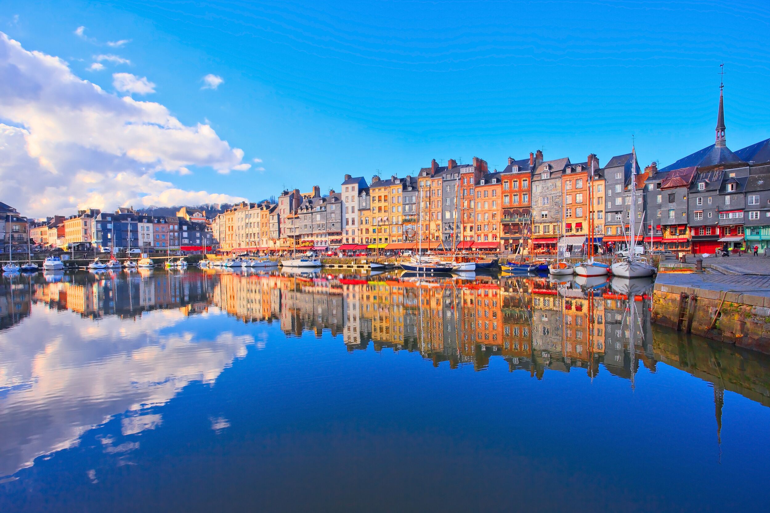 A waterfront with colorful buildings, a church spire, and boats.