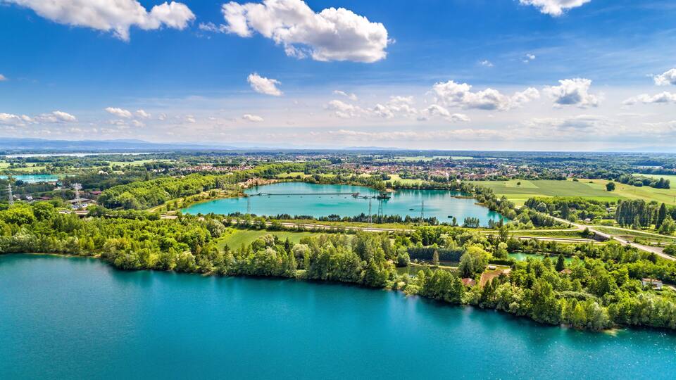 A large lake surrounded by lush greenery and a town in the distance.