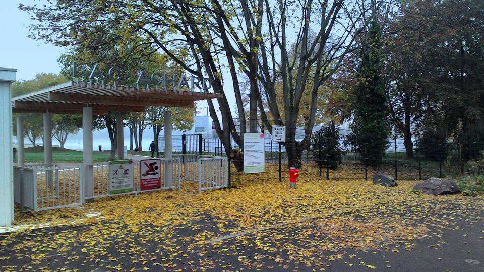 A park entrance with a covered shelter, a sign indicating no parking, and a red fire hydrant.