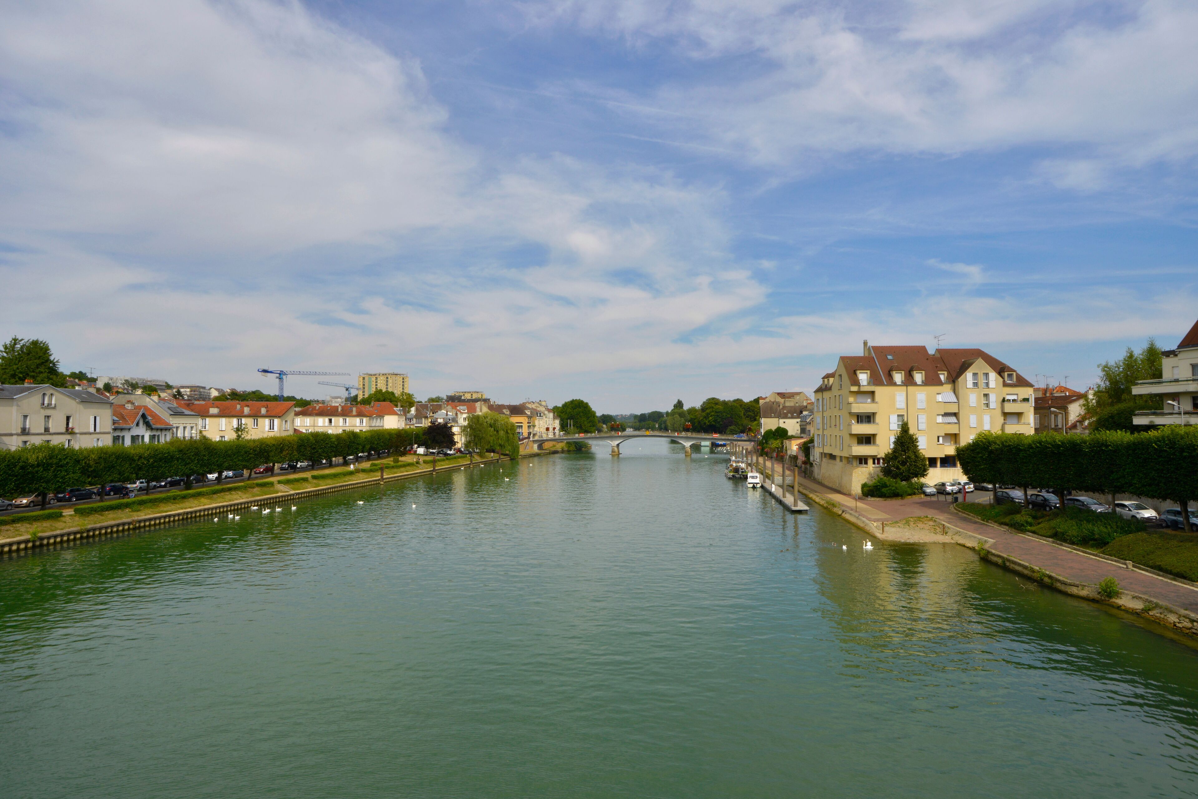 A river with a bridge, buildings, and parked cars.